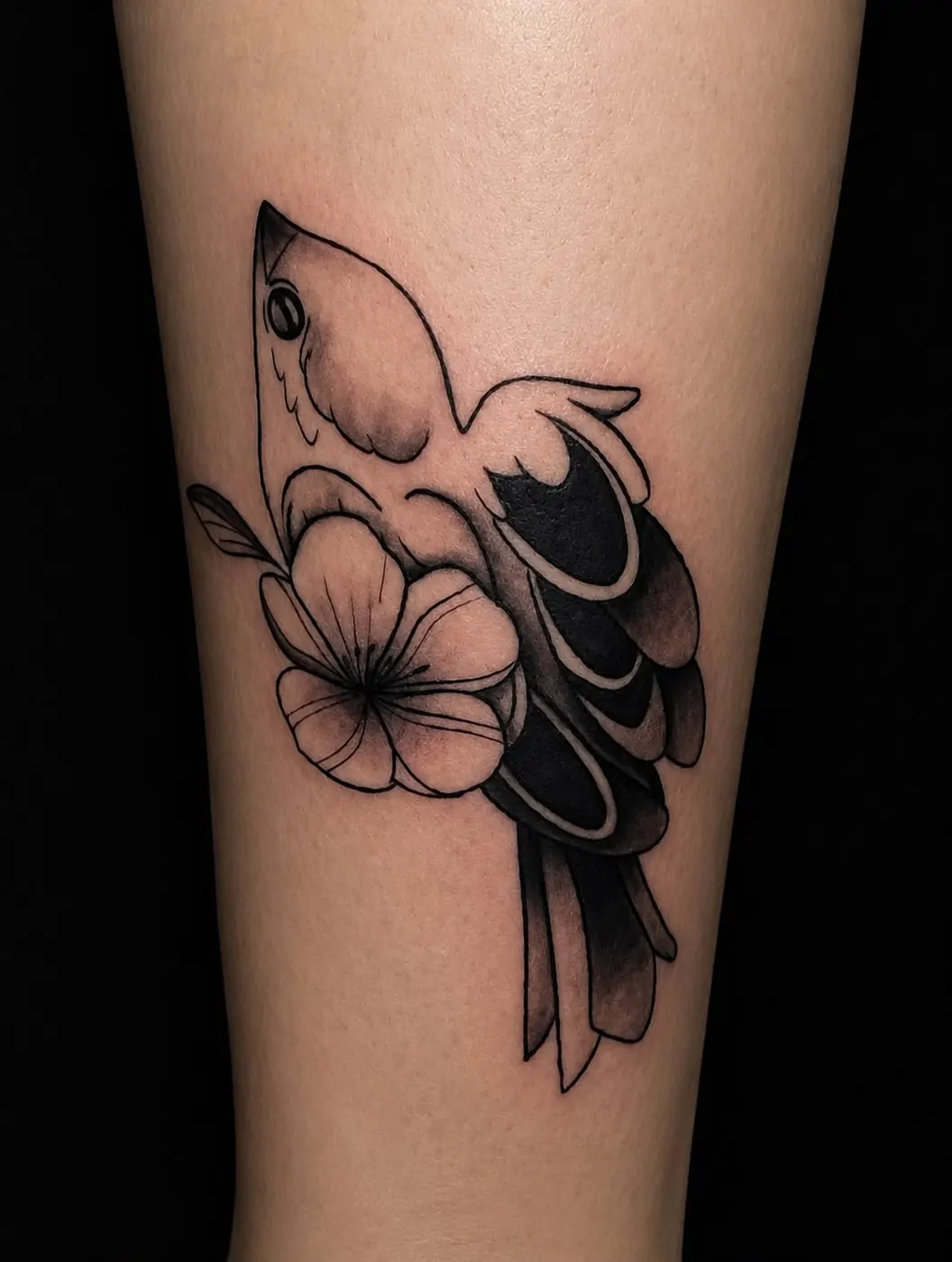 Tatuaje blackwork de ave y flor realizado por Sowii en Bogotá